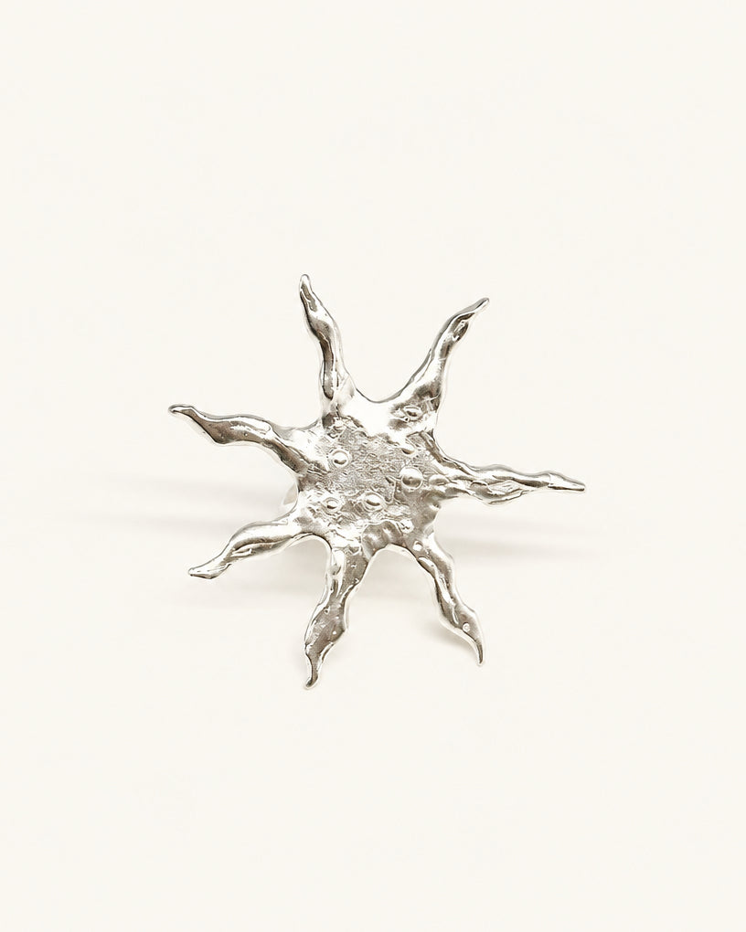 A silver-colored ring with a star-shaped design, featuring multiple branches or protrusions.